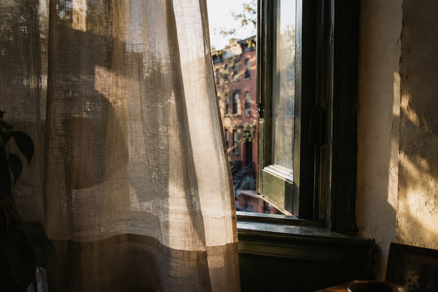Sunlight through a linen curtain at an open apartment window.